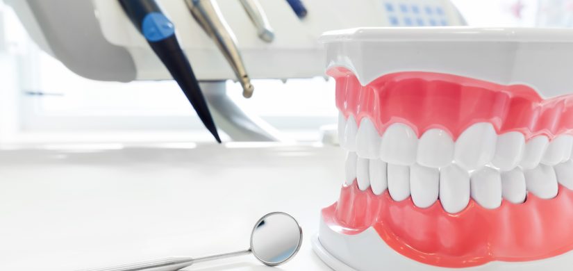 Clean teeth denture, dental jaw model, mirror and dentistry instruments in dentist's office.